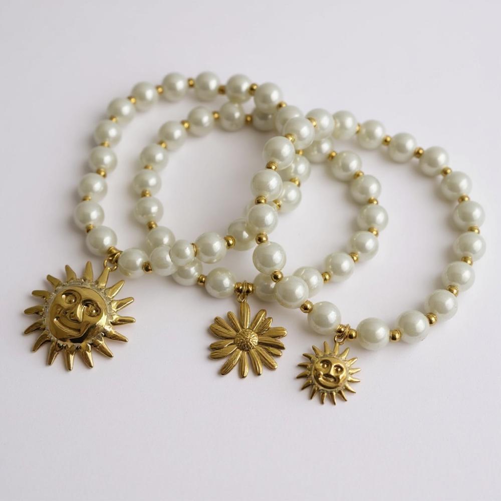 Bracelet en perles nacrées blanches avec pendentifs dorés (soleil ou marguerite), bijou personnalisable Gaou Bijoux